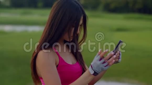 在公园用电话的运动女人适合女孩在电话里看新闻视频的预览图