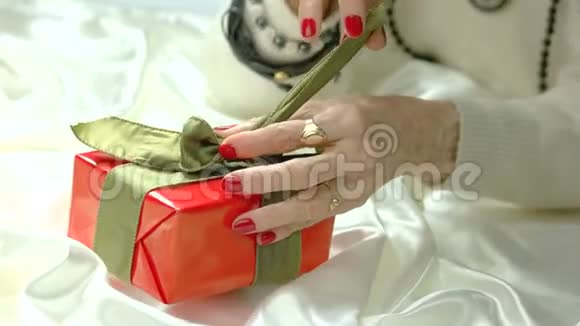 女人的手在礼品盒上解开蝴蝶结视频的预览图