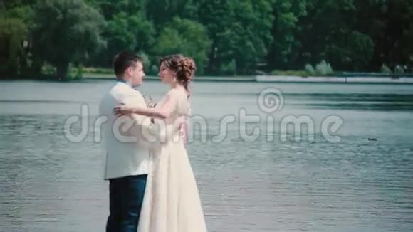 结婚纪念日美丽的一对夫妇享受他们的幸福站在码头上拥抱和亲吻结婚礼服花束视频的预览图