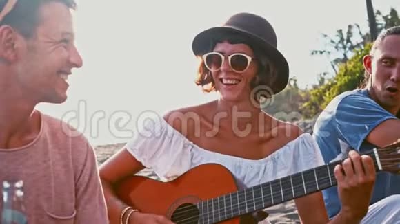 年轻人在海滩上玩得很开心在岛上度周末朋友们围着吉他快乐地唱歌视频的预览图