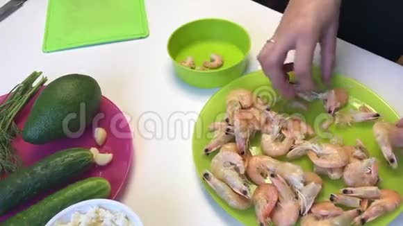 女人清理煮虾桌子上的下一个是蔬菜和豆腐块视频的预览图