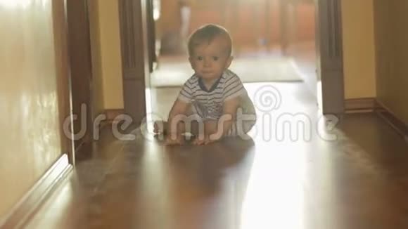 1岁的男孩在木地板上朝镜头爬去视频的预览图