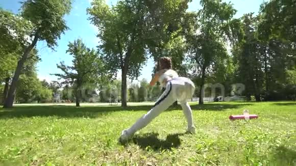 年轻的女运动员在公园户外做蹲操适合女孩锻炼她的核心和滑翔与体重视频的预览图