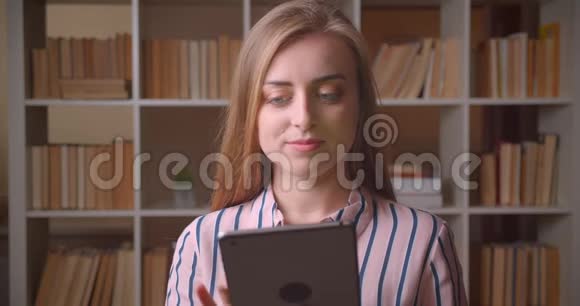 用平板电脑拍摄年轻漂亮的白种人女学生的特写肖像并在镜头中显示绿色屏幕视频的预览图