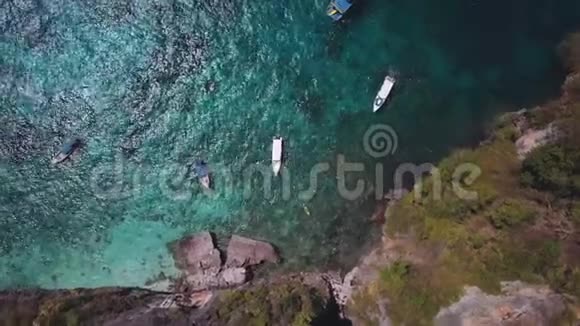 白色游艇在热带海洋附近的石灰岩岩石在靠近石灰石岩石的热带海中鸟瞰白色游艇空中飞行视频的预览图