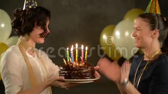 生日女孩拿着一个巧克力蛋糕和蜡烛并试图咬掉一块她的朋友很漂亮视频的预览图