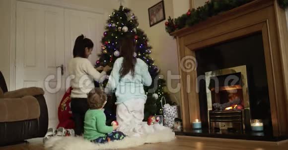 快乐的孩子们一起装饰圣诞节和新年树可爱的儿子看着妈妈吃苹果视频的预览图
