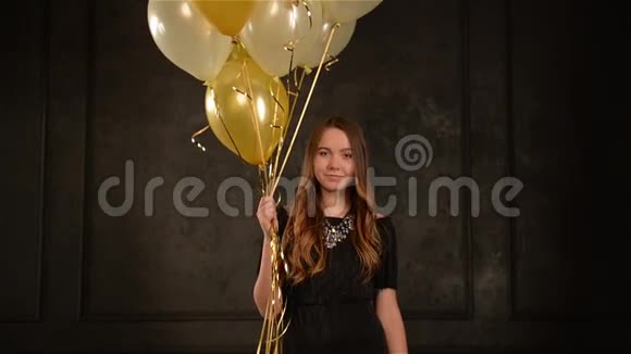 派对女郎手中拿着空气气球站在金色和银色的纸屑中长发少女微笑视频的预览图