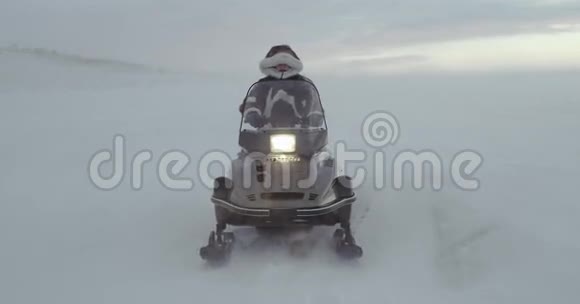 一个穿着驯鹿大衣带着毛皮帽的冒险者在暴风雪中看着一辆雪车2016年北极探险4k视频的预览图