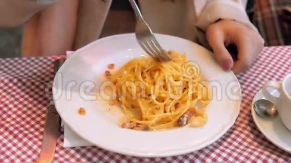 用意大利面条近距离观看盘子年轻快乐的女人坐在咖啡馆里忙碌了一天后吃意大利面视频的预览图