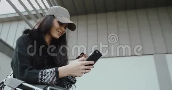 可爱的黑发女孩带着棒球帽拿着信用卡用她的智能手机爱尔兰2016年4k红史诗高清镜头视频的预览图