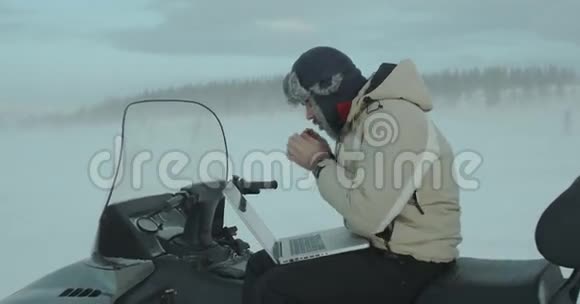 在恶劣的冬季环境中使用雪上移动笔记本的年轻程序员他正在用手来取暖视频的预览图