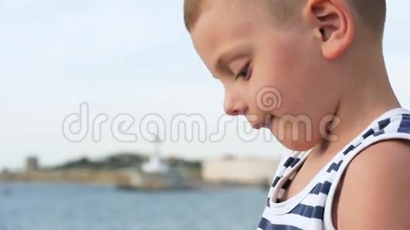 穿着条纹衬衫的小男孩透过望远镜看海港前视频的预览图