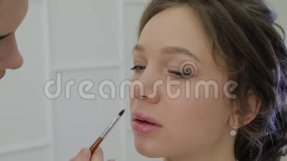 化妆师用刷子在嘴唇上涂口红美丽的女人唇部涂抹唇彩视频的预览图