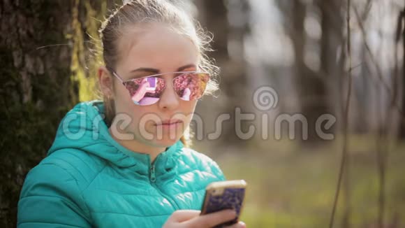 戴眼镜的少女正在使用智能手机视频的预览图