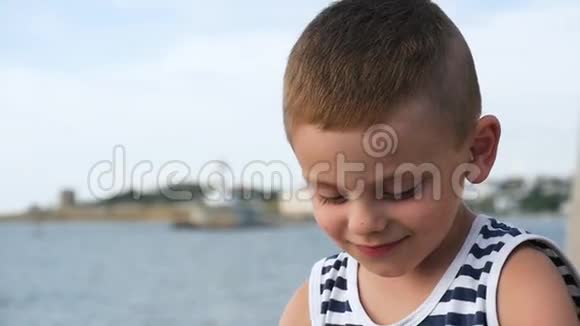 夏天大海背景上穿着条纹衬衫的微笑和健谈的小男孩视频的预览图