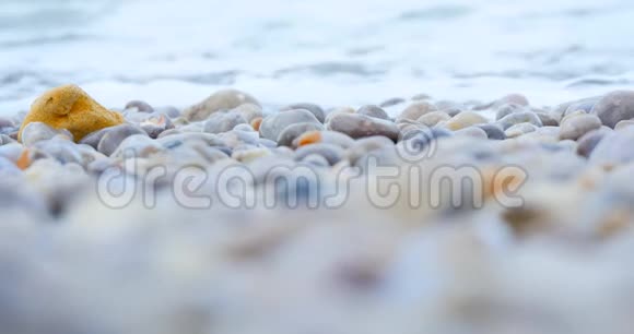 海浪覆盖着大海的石滩特写黄色的石头视频的预览图