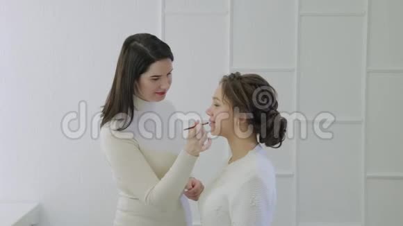 化妆师用刷子在嘴唇上涂口红美丽的女人唇部涂抹唇彩视频的预览图