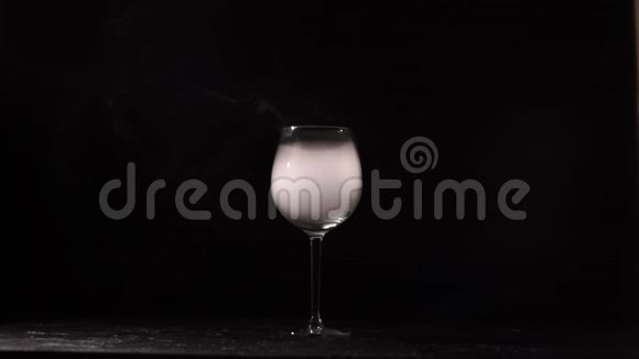 人将葡萄酒倒入带有黑色背景的液氮的玻璃杯中视频的预览图