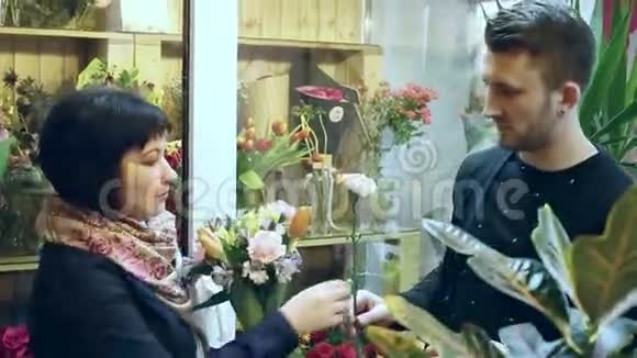 在花店里花商拿着一束花告诉客户它是从哪种花组成的视频的预览图