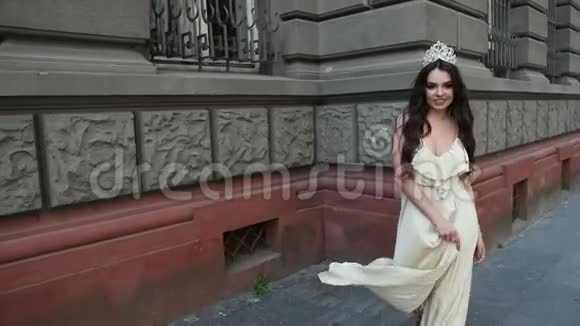 穿着浅色连衣裙戴着皇冠的深色女孩模特在街上拍照视频的预览图