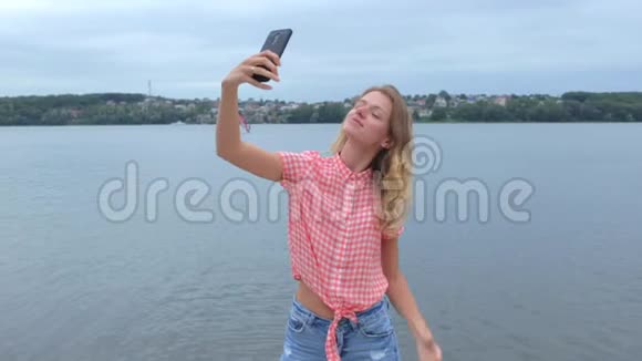 女人在湖边慢动作拍手机视频的预览图