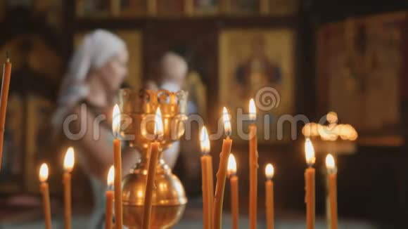 蜡烛在前景母亲带着婴儿在模糊的背景教堂视频的预览图