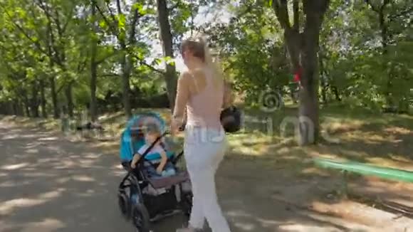 stadicam年轻母亲在公园推婴儿车镜头视频的预览图