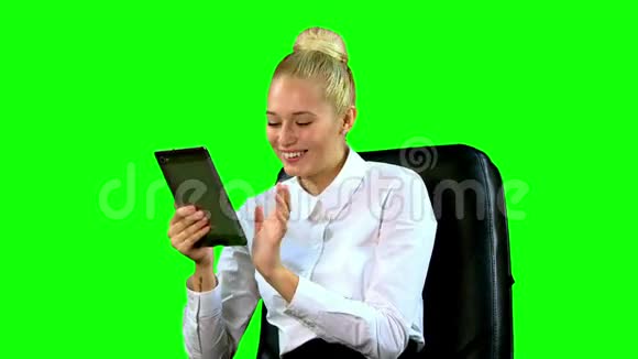 带着平板电脑的年轻女人在椅子上笑绿色屏幕中东视频的预览图