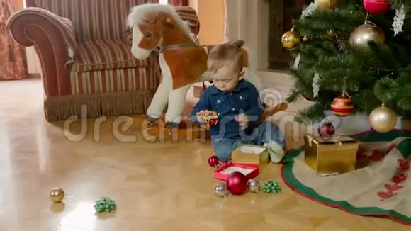 一岁的小男孩在客厅的圣诞树下玩耍视频的预览图