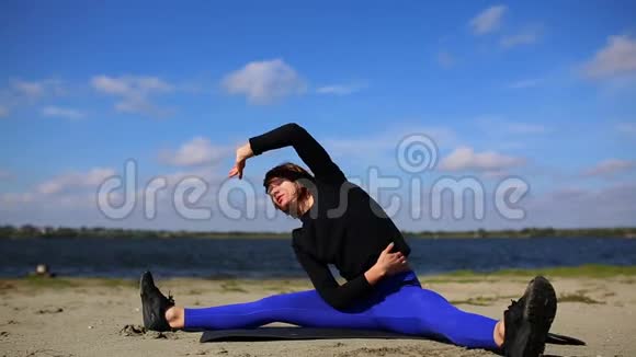 河岸上的女孩在经过一次艰苦的锻炼后进行肌肉的伸展和放松健身和瑜伽视频的预览图