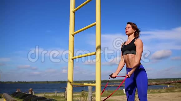 穿着蓝色紧身裤的可爱运动型深色头发的女人在街上锻炼身体增强手部肌肉视频的预览图