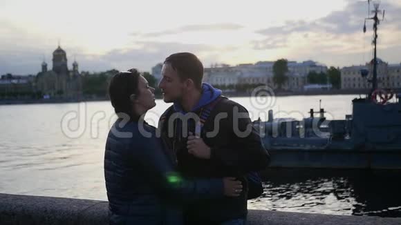 一对相爱的夫妇站在城市里一条河附近的海滩上亲吻慢动作1920x1080全高清视频的预览图