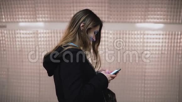布鲁内特女士站在地铁站台上使用智能手机女孩在等火车时上网视频的预览图