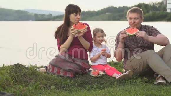 大家一起吃西瓜快乐的一家人在夏日的池塘边野餐视频的预览图