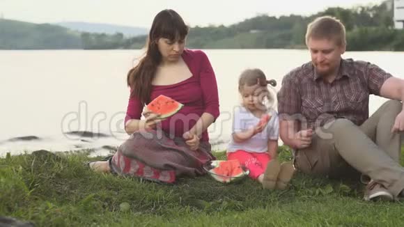 大家一起吃西瓜快乐的一家人在夏日的池塘边野餐视频的预览图