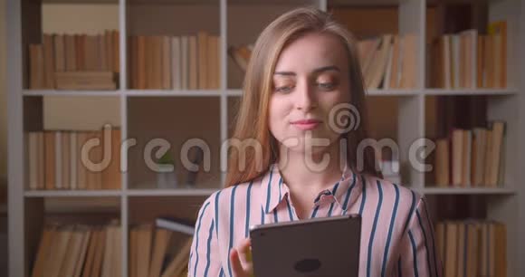 年轻漂亮的白种人女学生用平板电脑特写肖像并在镜头中显示绿色彩色屏幕视频的预览图