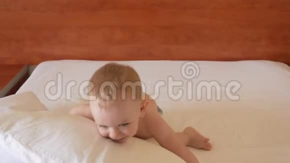 可爱的蹒跚学步的男孩在床上玩枕头笑他把它扔到旁边视频的预览图
