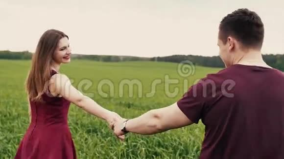 浪漫的年轻情侣牵着手走在一片长草的田野里慢莫稳定射击视频的预览图