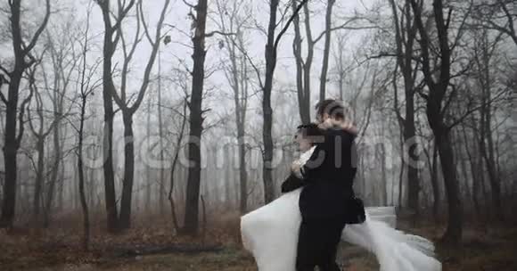 新婚夫妇快乐新郎在树林里旋转新娘慢动作4k视频的预览图