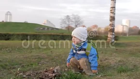可爱的孩子在日落时和他妈妈在公园里玩他坐着然后站起来镜头围绕着男孩转视频的预览图