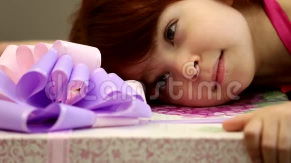 小可爱的快乐女孩抱着巨大的礼物盒粉红色紫色的丝带蝴蝶结看着近在咫尺的享受视频的预览图