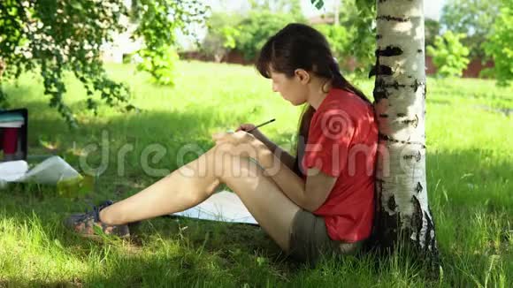 黑发年轻女子在公园里画画视频的预览图