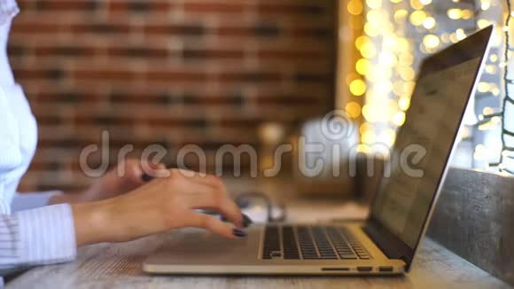一张侧面照片拍摄的是一位年轻漂亮女子坐在咖啡厅的木桌旁忙着操作笔记本电脑的手视频的预览图