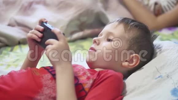 躺在床上的便携式游戏机男孩视频的预览图