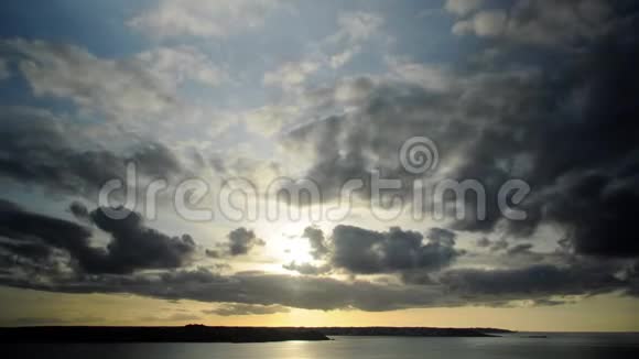 夕阳西下在悬崖和海洋之上有黑金色的云层和傍晚的太阳视频的预览图