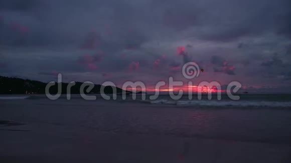 日落时的海景倒映在潮湿的沙滩上海浪涌来有伞的摩托艇视频的预览图