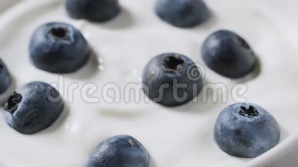 特写蓝莓在天然酸奶旋转4k水果背景视频的预览图