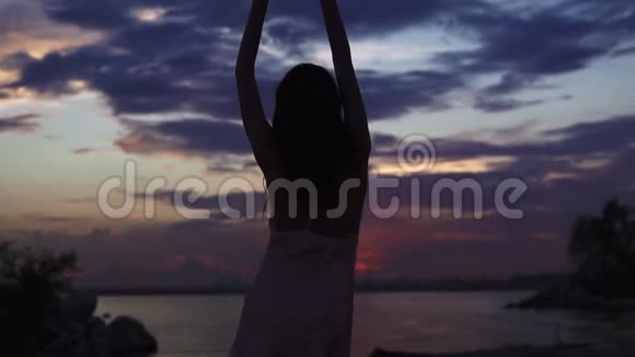 海边日落时跳舞的女孩剪影慢动作视频的预览图