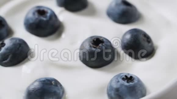 特写蓝莓在天然酸奶旋转4k水果背景视频的预览图